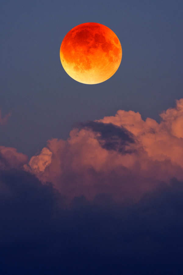 Big blood moon with yellow clouds in blue sky