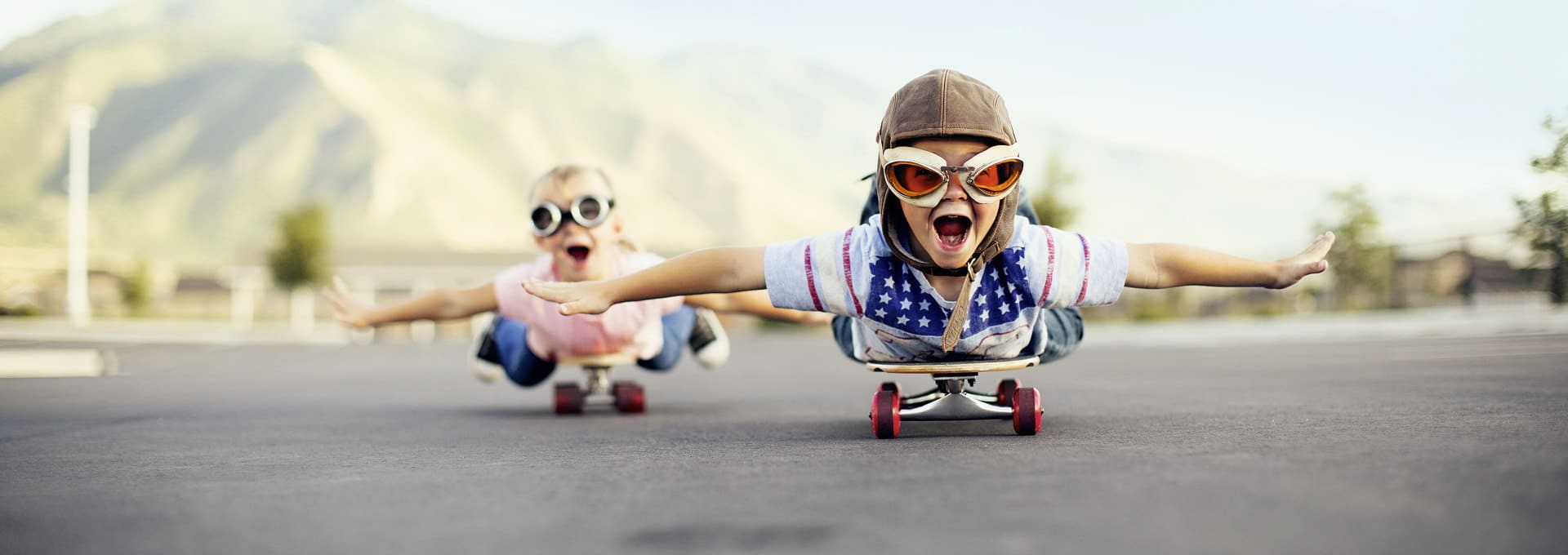Zwei Kinder flitzen auf der Skateboards auf der Straße entlang