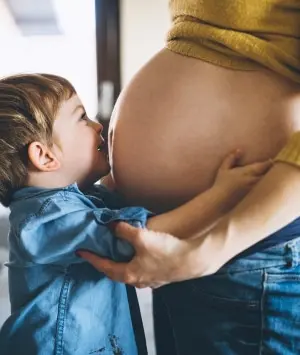 Sohn küsst Bauch von schwangeren Mama