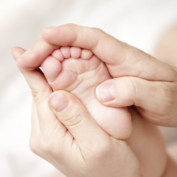 Hände umfassen Babyfuß
