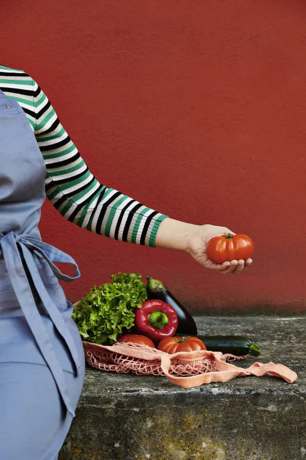 Frau hält Tomate in der Hand