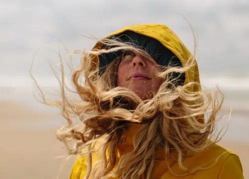 Resilienz_Frau am Strand mit Haaren im Wind