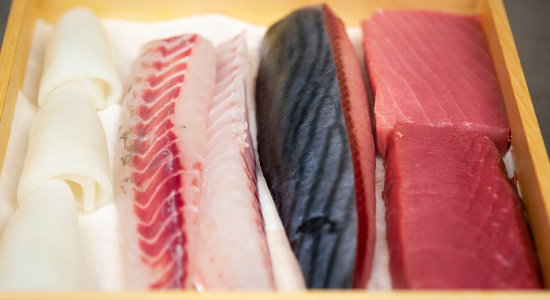 Verschiedene-Fische-fuer-Sushi-Zubereitung-in-Holzkistchen